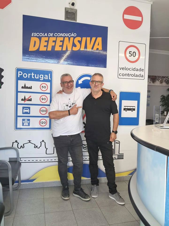 O instrutor com um antigo aluno, em frente à parede de sinais da escola