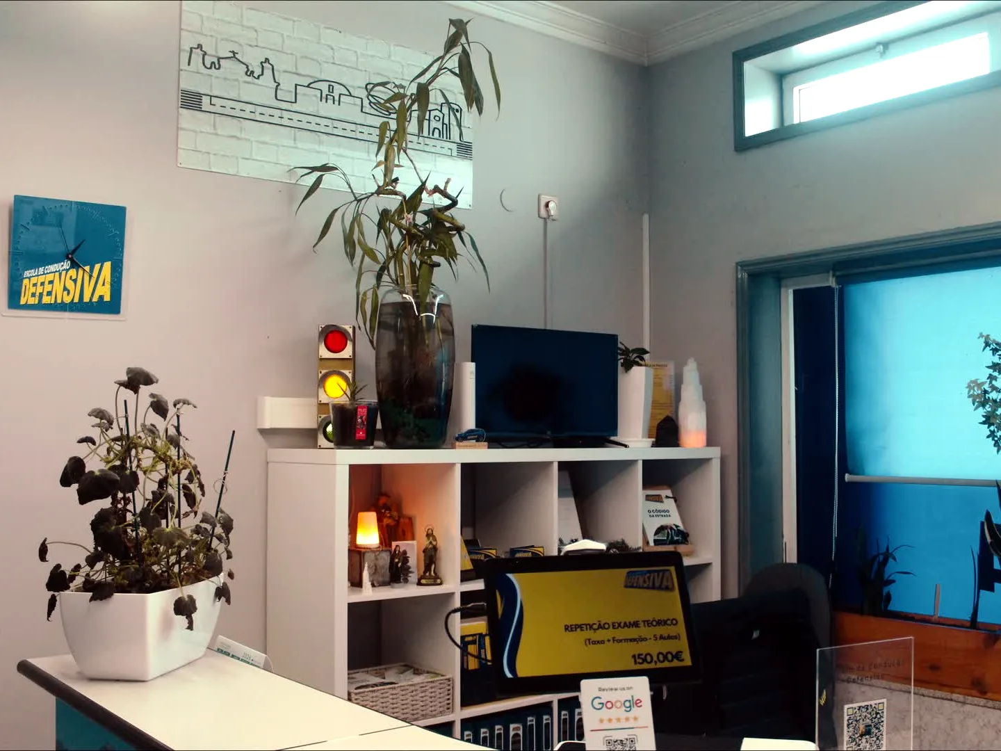Receção da escola, com plantas, semáforo decorativo e o logótipo Defensiva na parede